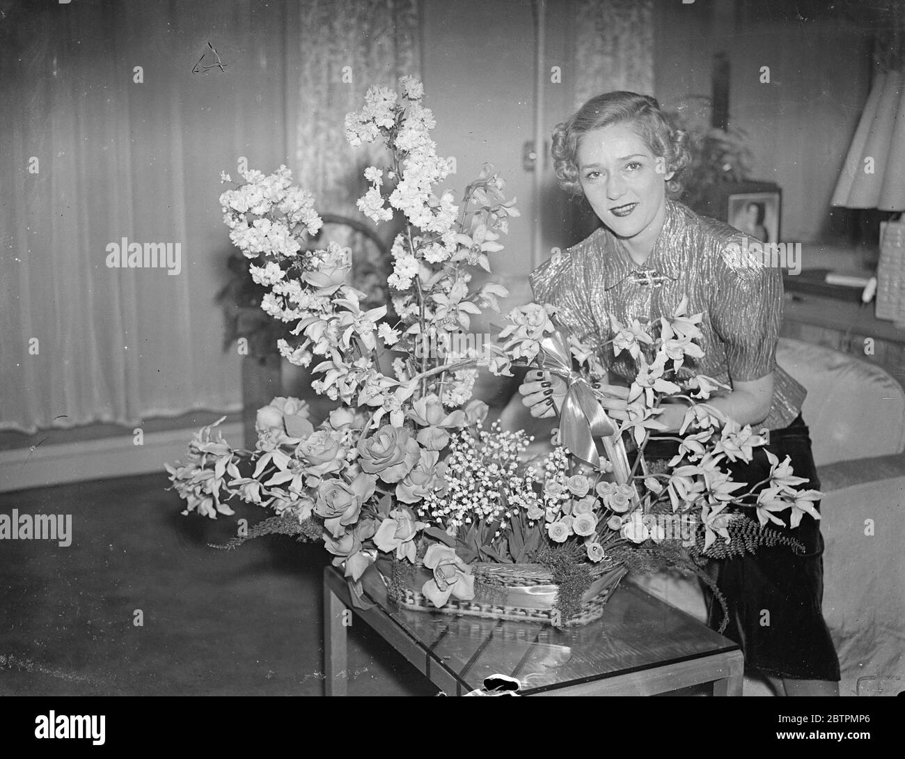 Blumen von ihrem Verlobten. Mary Pickford gibt Empfang in London. Mary Pickford, die "Welt" s Sweetheart, die nach London kam, um ihren Verlobten Charles ' Buddy ' Rogers, der Filmschauspieler und Bandleader, zu begleiten, gab einen Empfang in ihrem Londoner Hotel. Sie plant, zur Krönung in London zu bleiben. Foto zeigt, Mary Pickford arrangiert einen Korb mit Blumen, schickte sie von Buddy Rogers, in ihrer Suite bei Claridge ' s. 10 März 1937 Stockfoto
