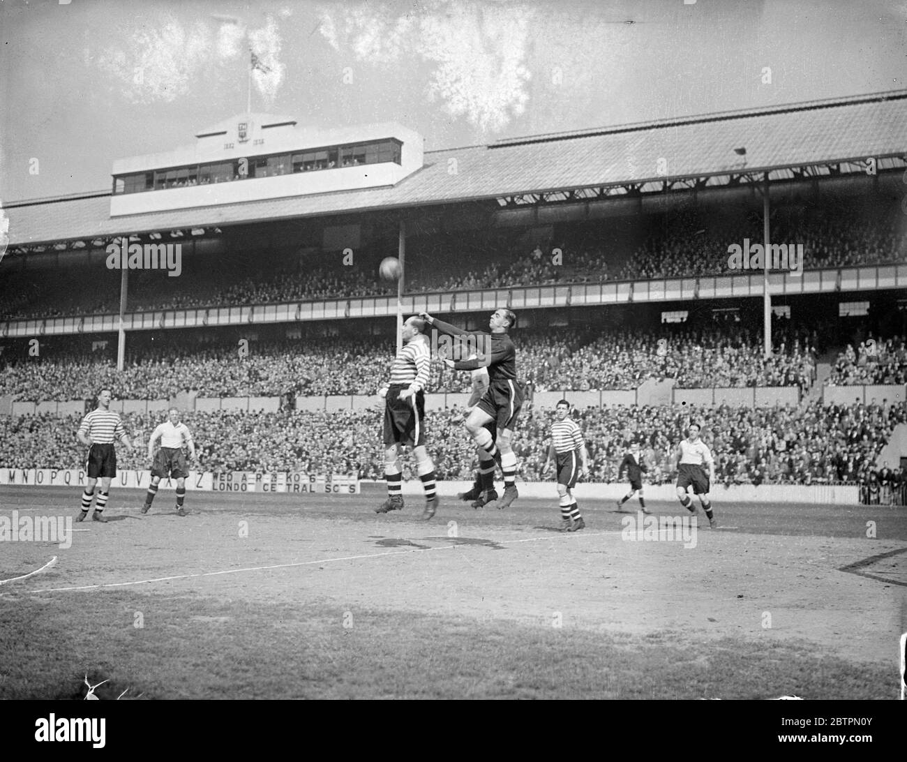 Voll auf Besuche Spurs. Tottenham Hotspur und Fulham trafen sich in Londons zweiter Division Derby in der White Hart Lane. Foto zeigt Tootill, Fulhams Torhüter, der vor Spurs-Attacke klar schlug. Sporen in Weiß. 24. April 1937 Stockfoto