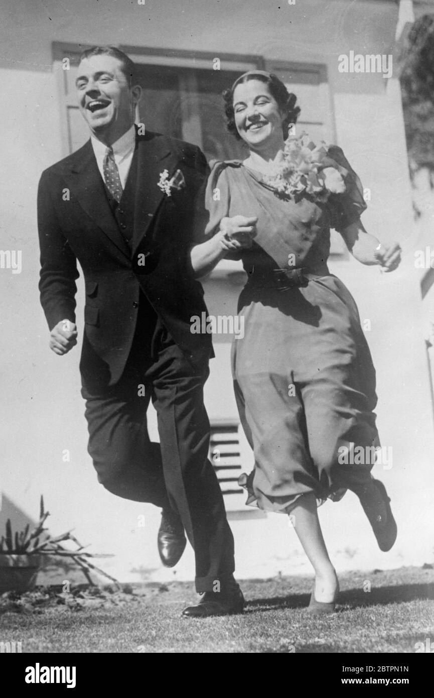 Eine echte, weggeratenen Ehe. Fotoausstellungen: Lyle Talbot, der Filmschauspieler, und seine Braut, ehemals Marguerite Cramer, laufen nach ihrer Heirat in Hollywood, Kalifornien, lachend vor ihren Freunden. Nur wenige enge Freunde waren bei der Zeremonie anwesend. April 1937 Stockfoto