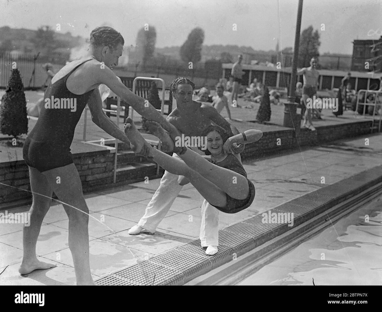 Obligatorisches Eintauchen. Gesungen von zwei kräftigen Gefährten, wird dieses Mädchen Badende ein obligatorisches Bad in den Hornsey Open-Air-Bädern nehmen. Sie scheint nicht über die Aussicht jedoch alarmiert. 29 Mai 1937 Stockfoto