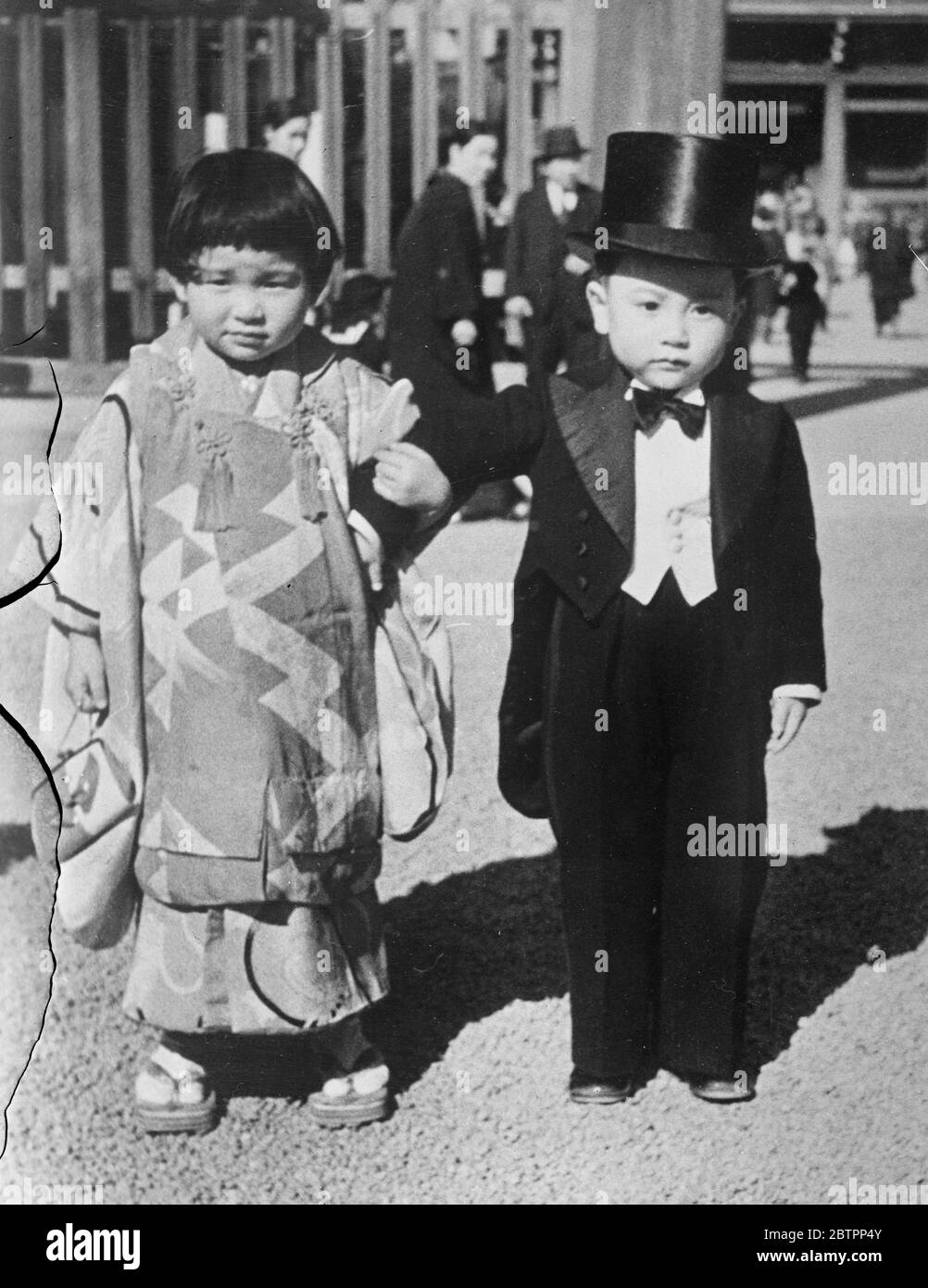 Er hält an seinen Geschichten fest!. In Japan ist es Brauch, dass Kinder im Alter von drei, fünf und sieben Jahren in bester Kleidung zum Schutzheiligtum gebracht werden, um für eine glückliche Zukunft zu beten. Seit Ausbruch der Feindseligkeiten in China, 80% der Jungen in Militär- oder Marinehandkleidung gekleidet. Foto zeigt, ein kleiner Bürger von Tokio, der anscheinend keine militärischen Ambitionen hat, trägt seinen Hut und Schwanz, als er seine "Dame" zum Schrein führt. 28. Januar 1938 Stockfoto