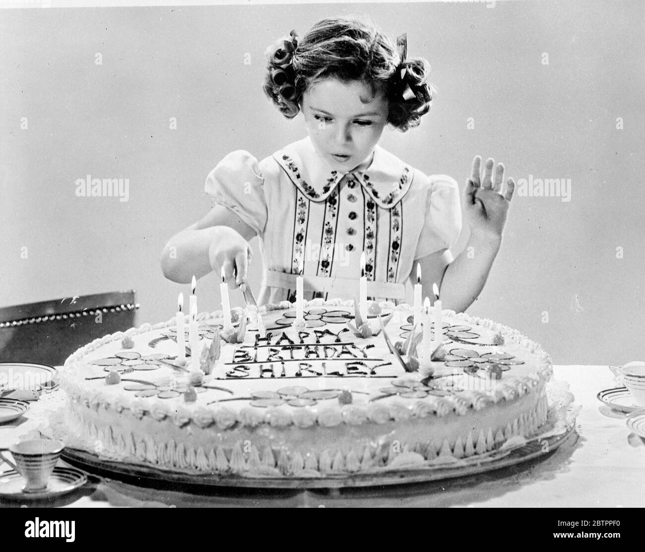 Shirley's Lucky Day. Feiert 9. Geburtstag. Shirley Temple, die Kinderfilmschauspielerin, schneidet ihren neunten Geburtstagskuchen, geschmückt mit neun Kerzen, in ihrem Hollywood-Haus. Shirley nahm sich Zeit für ihren neuen Film 'Lucky Penny', um zu feiern. Mai 1938 Stockfoto