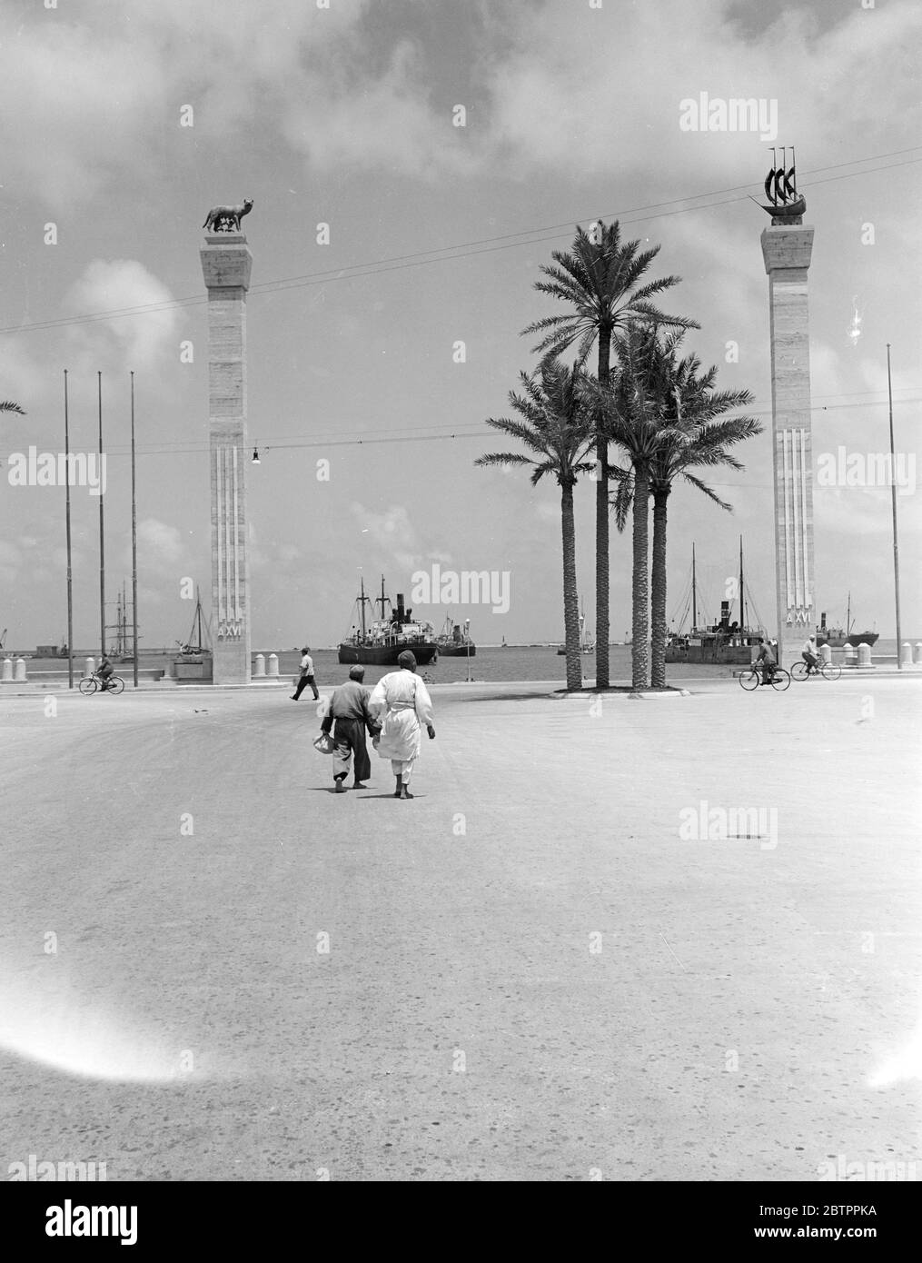 Libyscher Markt. Der Hafen, von der Piazza Castello aus gesehen. Die Symbole von Rom (links) und Tripolis sind auf zwei Säulen zu sehen, die im Jahr XVI der faschistischen Herrschaft, das heißt 1938, aufgestellt wurden Stockfoto