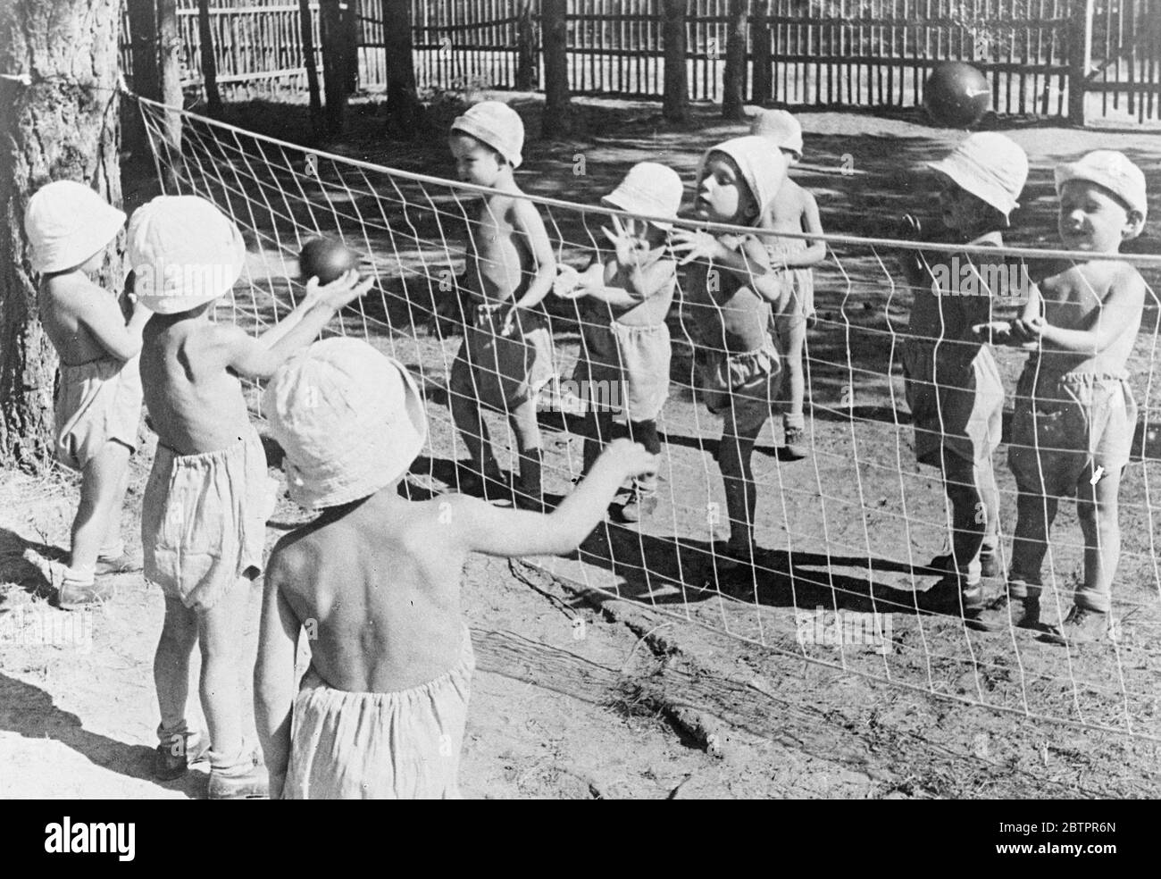 Ihr „Wimbledon!“. Ein kritischer Moment in einem Volleyballspiel in einem Kinderland Ferienhäuser in Moskau. Mit den winzigen Spielern passend in Shorts und Sonnenhüte gegart, haben sie keine Schwierigkeiten, Kohle zu halten, auch wenn das Spiel heiß ist. 27 Juni 1937 Stockfoto