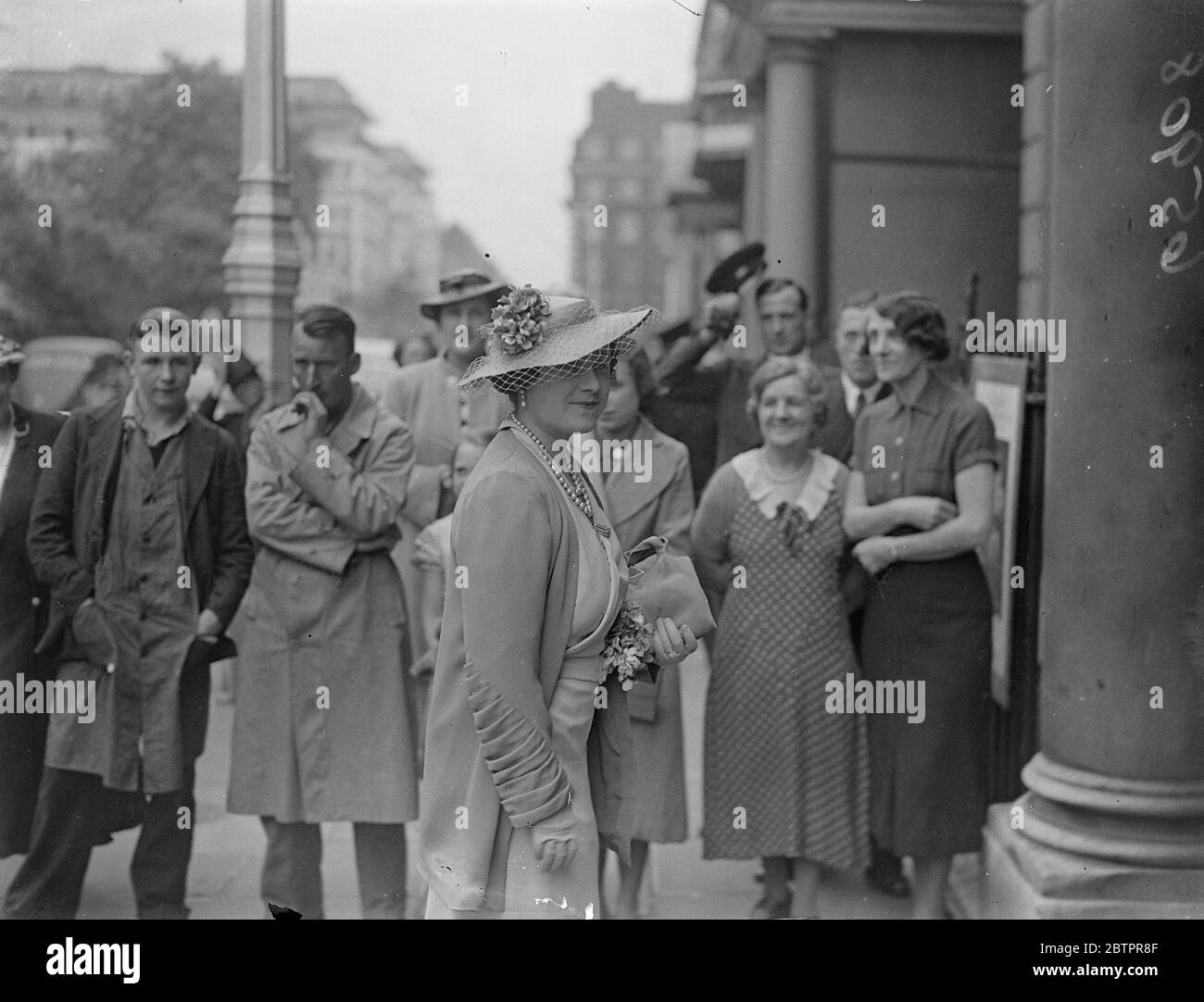 Die neue Queens Hut Mode. Die Königin, die einen großen Hut mit einem Netz Vail trägt, als sie die Ausstellung des britischen Landlebens auf dem Grosvenor Square besucht. Ihre Majestät war in zwei Schattierungen von Purpur gekleidet. 24 Juni 1937 Stockfoto