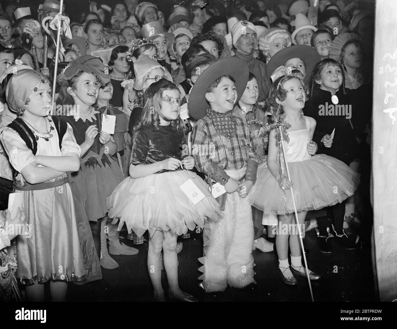 Echte Cowboy-Guffaw. Ein kleiner Cowboy und seine Mitgäste in ausgefallenen Kleidern ließen sich in einem Lachenbruch bei der Punch and Judy Show beim Lord Mayor's Ball für Kinder im Mansion House, London, nieder. Januar 1938 Stockfoto