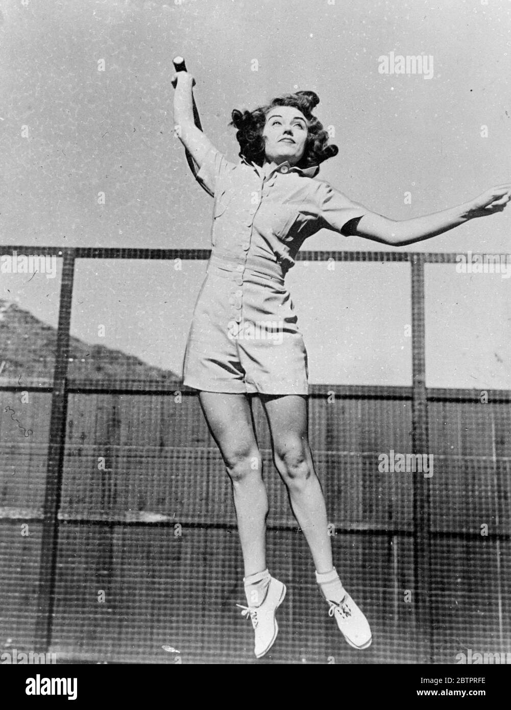 Der Himmel ist die Grenze. Fay Wray, die Hollywood-Filmschauspielerin, grinst ihre Zähne und springt nach einem hohen Ball in einem schnellen Tennisspiel im Palm Springs (Kalifornien) Tennis Club. Miss Wray's attraktiver einteiliger Anzug ist das neueste für den Urlaub in der Filmkolonie. 31 Dezember 1937 Stockfoto