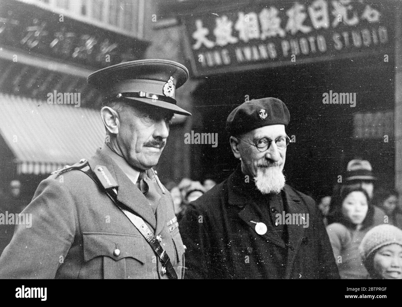 Soldat und Priester. Britischer Militärchef, sieht Flüchtlingsgebiet in Shanghai. Brig Gen Telfer Snollet, der die britischen Streitkräfte in Shanghai begeleitet hat, mit Pater Jacquinot am Hauptquartier des Internationalen Roten Kreuzes in Nantao, als die Gen das Flüchtlingsgebiet inspizierte. Pater Jacquinot organisierte und leitet nun die Sicherheitszone von Nantao, die für Flüchtlinge eingerichtet wurde. Es war aufgrund seiner Bemühungen, dass Unterstände für die Tausende aus ihren Häusern vertrieben errichtet wurden. 22 Dezember 1937 Stockfoto