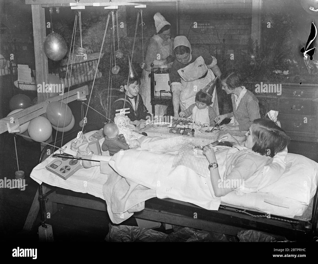 Nicht vergessen. Kinder genießen ihren Weihnachtstag im Krankenhaus. Kinder, die ihre Weihnachten in Londons Krankenhäusern verbringen mussten, wurden nicht vergessen. Krankenschwestern und Ärzte im Kinderkrankenhaus in der Great Ormond Street bringen eine saisonale Atmosphäre in die Stationen. Aber die Shows, die Studie, Patienten essen ihr Weihnachtsessen, serviert von einem der Krankenschwestern, in einer Station im Great Ormond Street Hospital, Bloomsbury. 25 Dezember 1937 Stockfoto