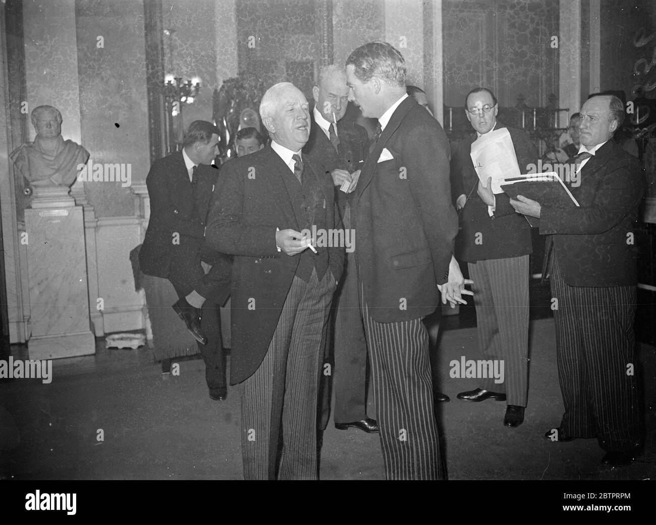 Eden hört sich 'Onkel Sam' an. Anthony Eden, britischer Außenminister, mit den Fingern, die sich hinter seinem Rücken verflochten, hört sich Norman Davis, amerikanischer Vertreter, während der Pause der Nine Power Conference on the Sino-Japanese Hostities, im Palais des Academies in Brüssel an. Herr Eden und Herr Davis haben während der Konferenz deutlich gemacht, dass Großbritannien und Amerika Tarife fordern würden, aber nur in Vermittlungsbemühungen. November 1937 Stockfoto