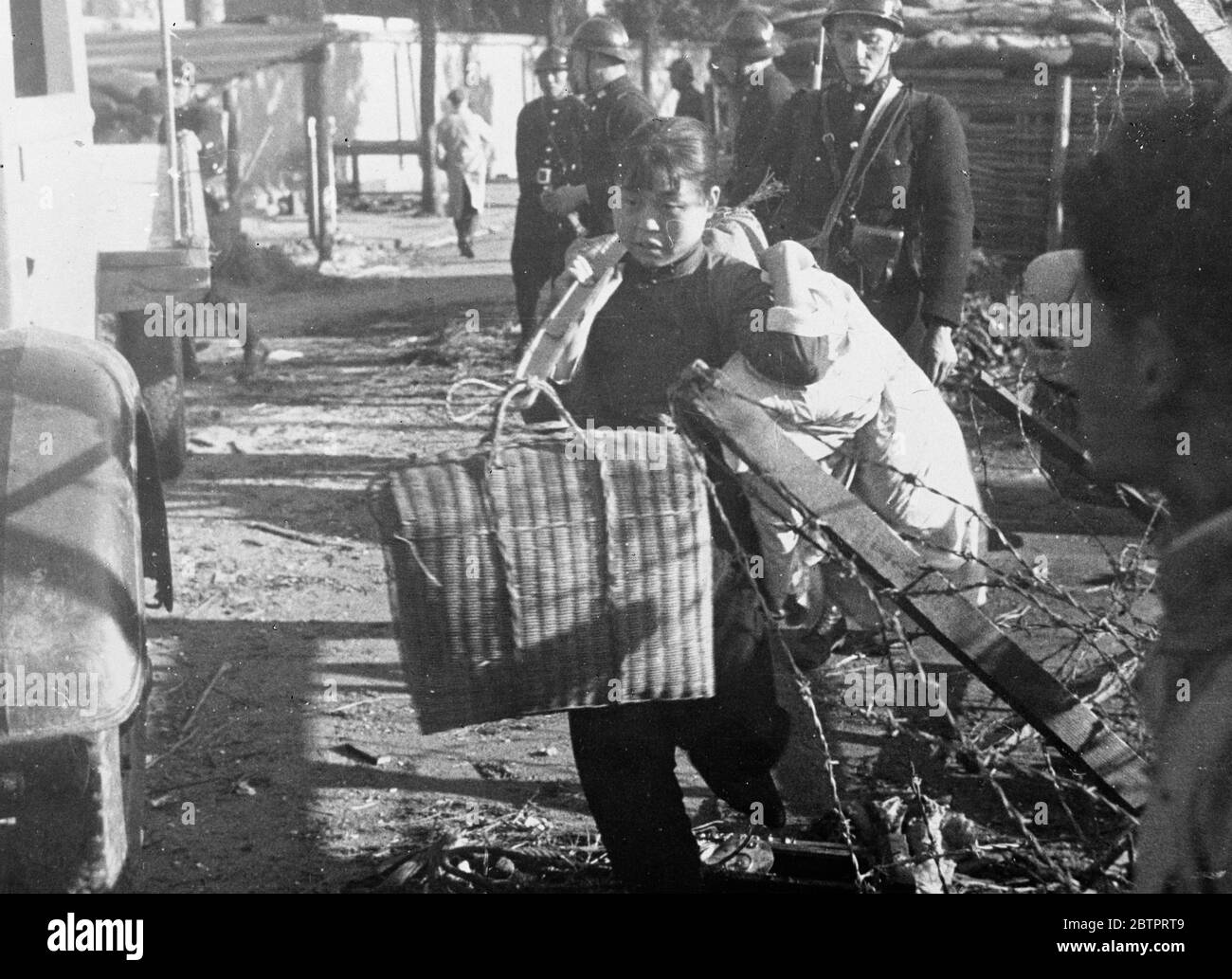 Ein Mädchen 'removal'. Bomb und Show gaben ihr Kraft. Ein chinesisches Mädchen aus Nantao, dem verwüsteten chinesischen Bezirk von Shanghai, belastet von ihrem Besitz, als sie Zuflucht in der Internationalen Siedlung suchte, die bereits mit 3 Millionen ihrer Landsleute und Frauen verklemmt ist, wird aufhören Angst erleuchtet die Fußstapfen des Mädchens, als sie eilte, um zu beherbergen. Dezember 1937 Stockfoto