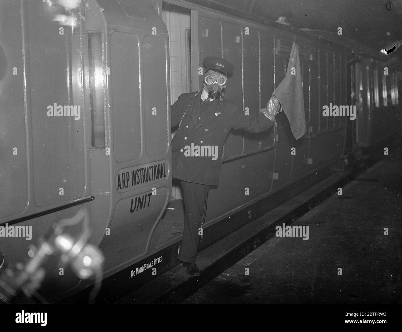 „bewacht“ gegen Gas. Anti Air RAID Training bei Euston. Und IMS Air RAID Vorsorge Mobile Instructional Unit war auf Euston Station, London, zu sehen. Die Einheit besteht aus zwei Fahrzeugen, einem Vortragswagen und dem anderen einem Dekontaminationswagen. Es wurde von der IMS Railway als Teil eines Programms zur Schulung ihrer Mitarbeiter in Air RAID Vorsichtsmaßnahmen zur Verfügung gestellt. Die mobile Einheit wird demnächst eine Tour durch das IMS-System in England, Schottland und Wales Unternehmen. Sie Eisenbahn beabsichtigt, fast 23,000 ihrer 230,000 Arbeiter in Anti-Luftangriffsarbeit auszubilden. Foto zeigt, ein Wächter in einer Gasmaske Markieren eines Zuges Stockfoto