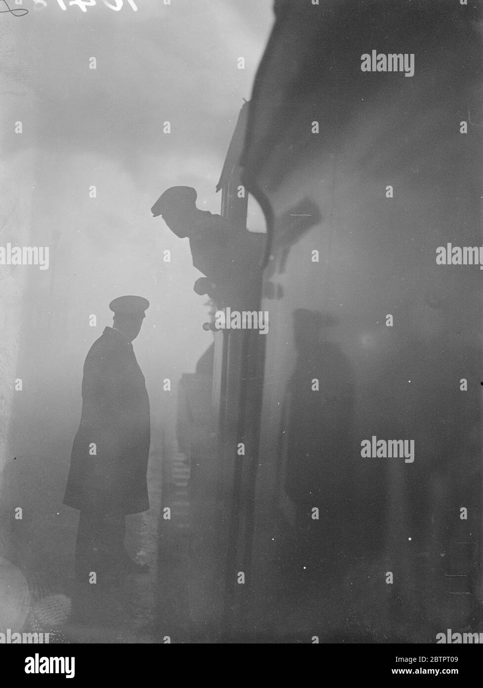 Nebel verlangsamt sich, London. Tausende Londoner wurden auf ihrem Weg zur Arbeit durch den dichten weißen Nebel, der die Transportdienste legte, aufgehalten. Foto zeigt, ein Motorfahrer, der mit einem Wächter am Bahnhof Liverpool Street über den Nebel diskutiert. 18. Oktober 1937 Stockfoto