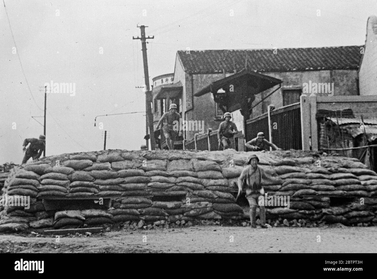 Chinesische Truppen überwinden ein Hindernis. Chinesische Soldaten, die eine Sandsack-Barrikade "in ihrem Schritt" Trommler gegen die Japaner am Rande von Shanghai kämpfen. 25. November 1937 Stockfoto