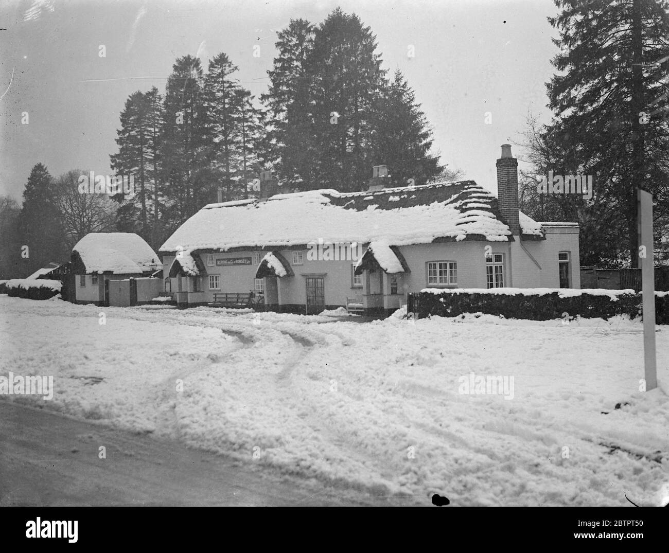 Schnee macht ein Bild. Schnee trägt zur Bilderlichkeit dieses strohgedeckten Gasthauses in Cadnum, Hampshire bei, wenn ein tiefer weißer Teppich nach einem heftigen Schneesturm die ganze Landschaft bedeckt. 10 Dezember 1937 Stockfoto