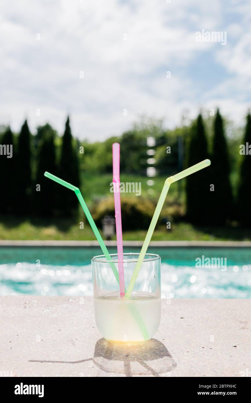 Ein Glas Limonade mit drei Strohhalmen am Schwimmbad Stockfoto