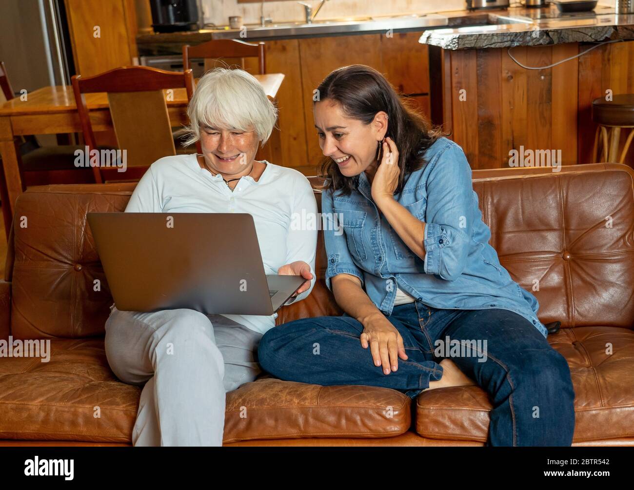 Happy Couple Video-Anrufe Freunde und Familie mit Laptop. Freundinnen online genießen zusammen das Leben zu Hause Streaming Video, Nachrichten oder Anruf f Stockfoto