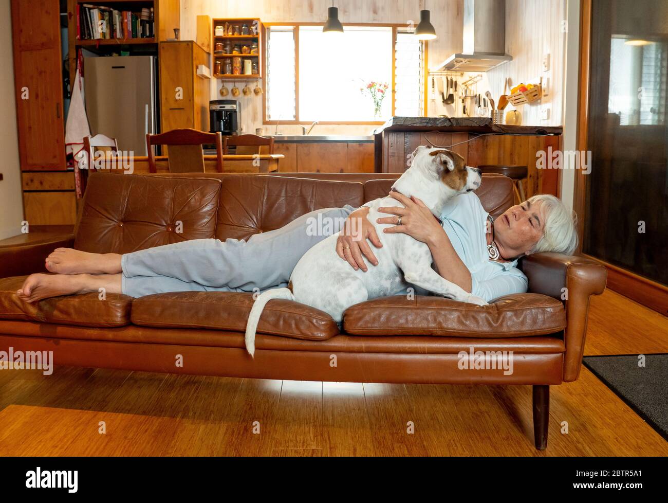 Selbstbewusste gemischte Rasse Frau lieben und kuscheln ihren niedlichen Haustier Hund genießen das Leben zu Hause zusammen. Positives Bild des Coronavirus Ausbruch zu Hause bleiben und ein Stockfoto