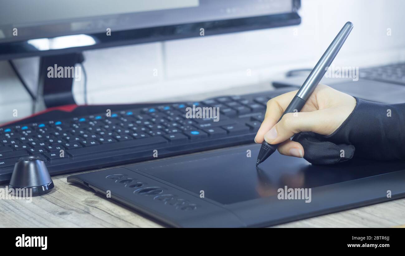 Die Hand einer Frau in einem speziellen Handschuh zieht sich auf ein grafisches Tablet. Freiberuflich. Designer Illustrator zeichnet Comics, Skizzen. Digitales Tablet, visuell, multimedi Stockfoto