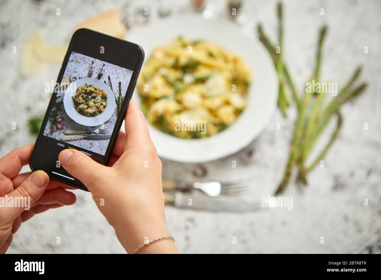 Frau, die ein Foto mit einem Smarthone von hausgemachten Tagliatelle Pasta mit cremigem Ricotta Stockfoto