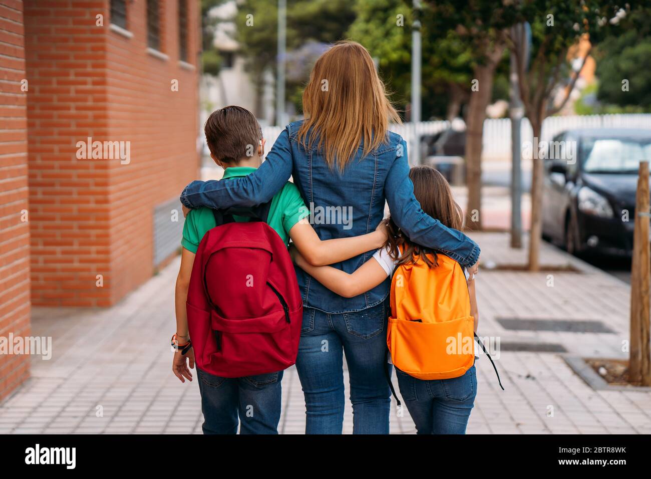 Mutter mit ihren Kindern gehen mit Masken in die Schule bei einer Coronavirus-Pandemie Stockfoto