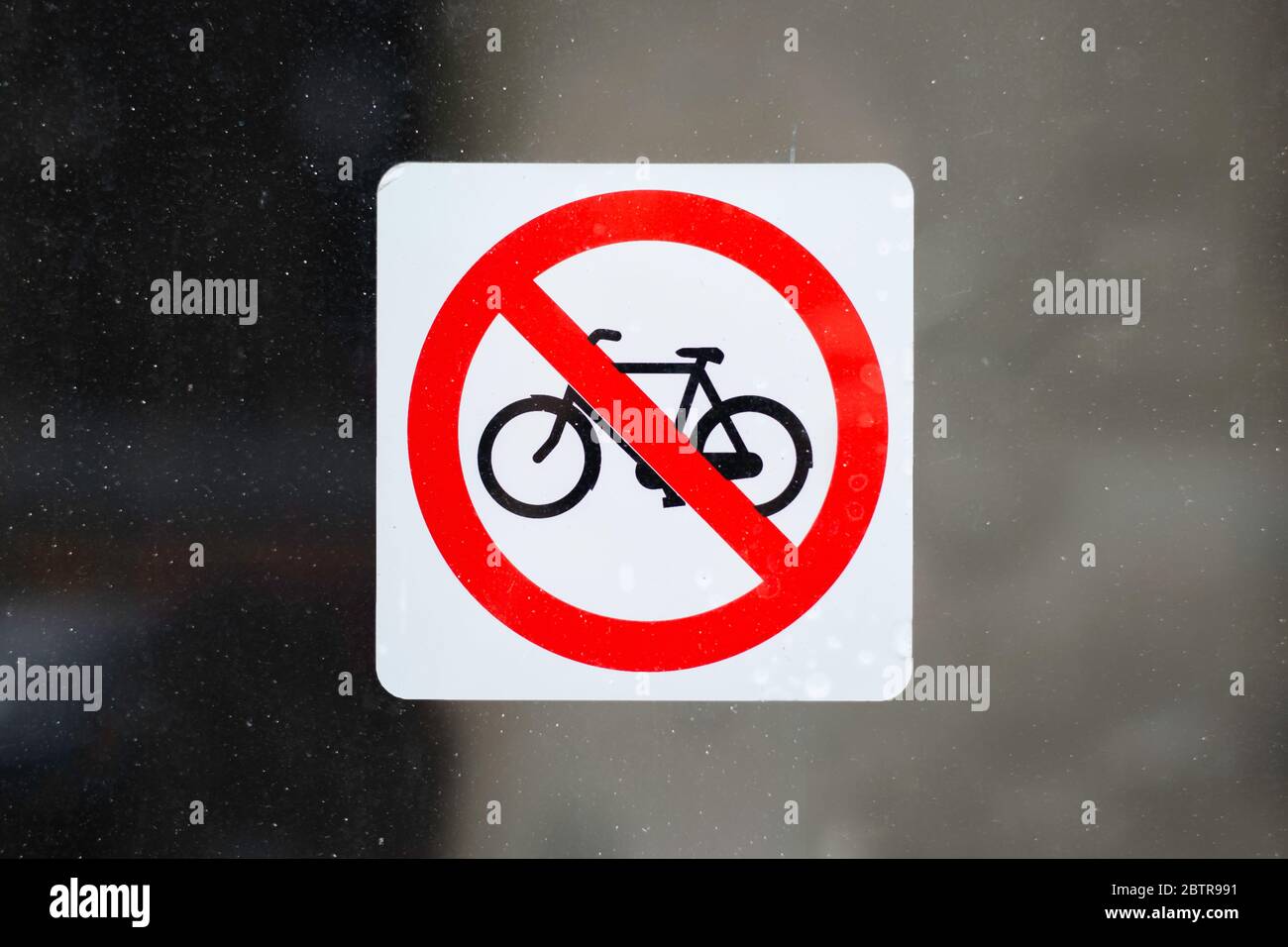 Rot mit weißem Aufkleber ohne Fahrradparkschild, auf einem schmutzigen Fenster. Fahrräder sind nicht erlaubt Stockfoto