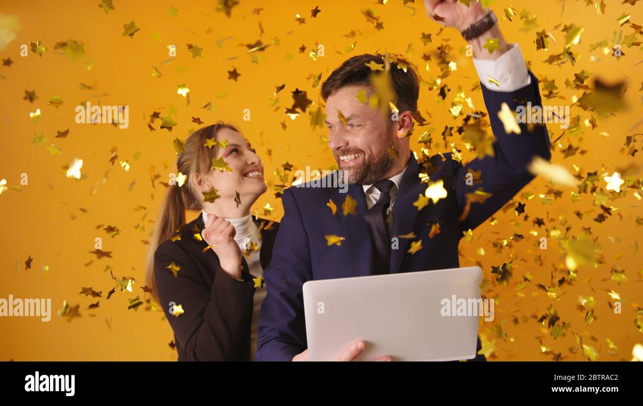 Junge Paare oder Geschäftspartner bekommen gute Nachrichten oder gewinnen die Lotterie. Aufgeregt feiern mit Konfetti. Stockfoto