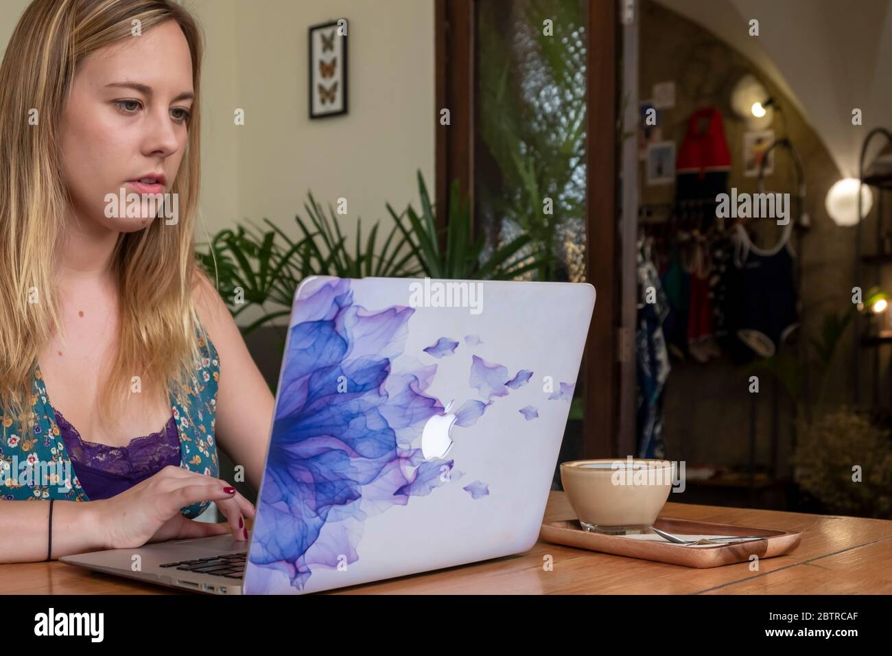 Eine Frau, die an einem Laptop arbeitet, mit einer Tasse Kaffee in einem Home Office oder Café Stockfoto