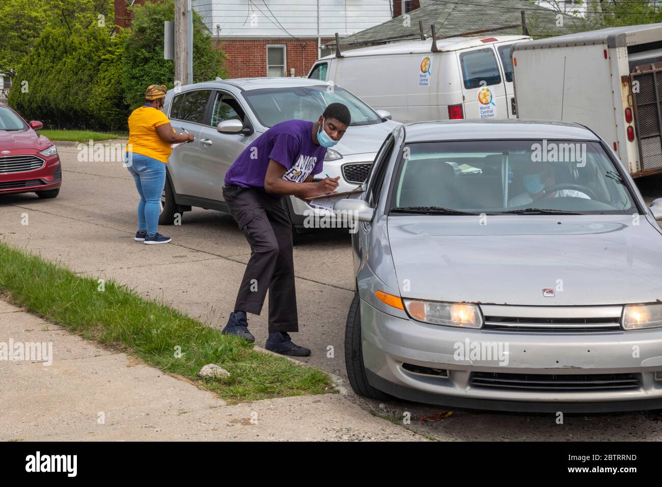 Detroit, Michigan - Freiwillige registrieren die Leute, um zu wählen, während sie für eine kostenlose Lebensmittelverteilung während der Coronavirus-Pandemie ankommen. Stockfoto
