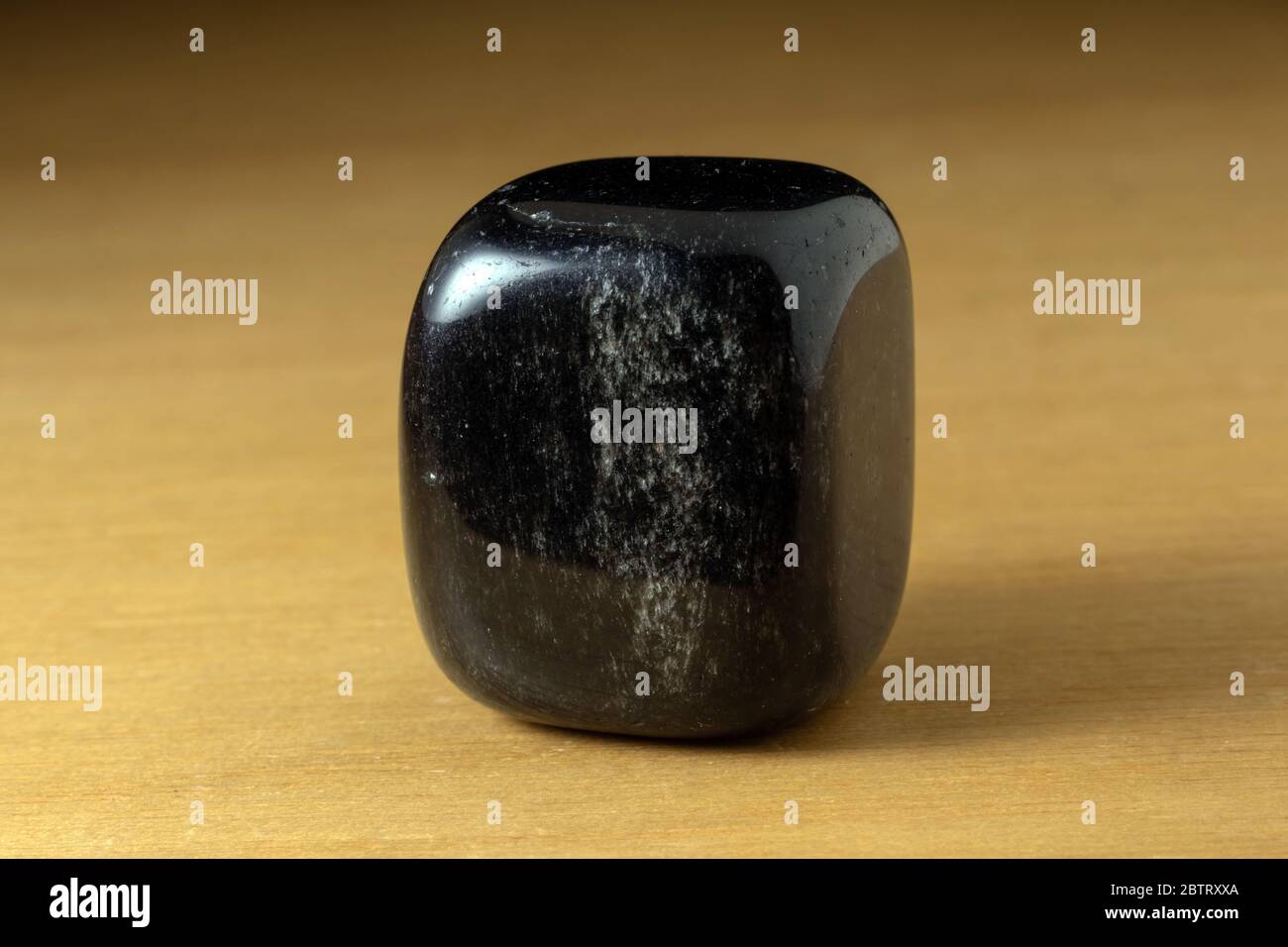 Schwarzer Onyx polierter Edelstein aus China über einem Holztisch Stockfoto