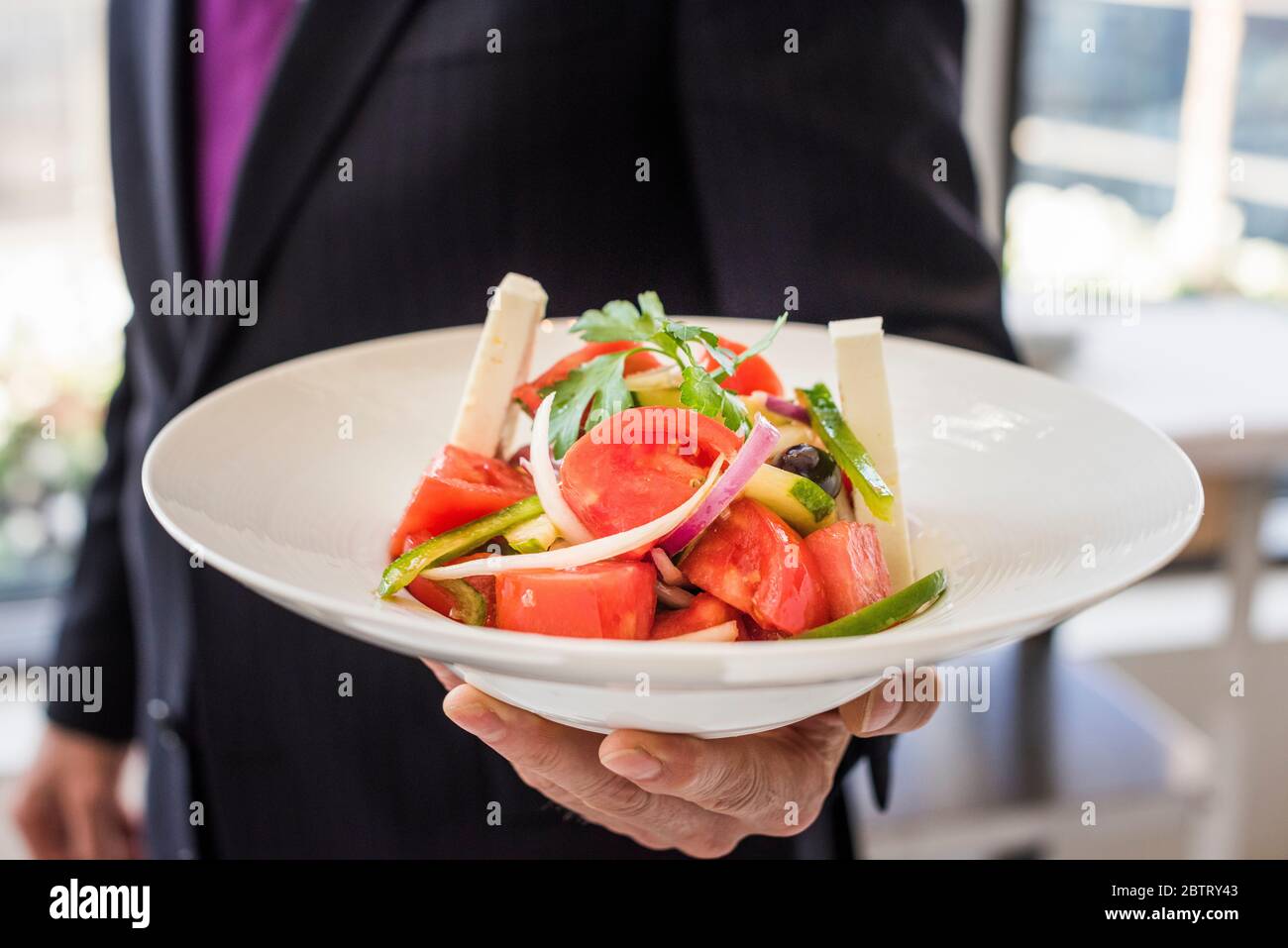 Mann hält griechischen Salat im Restaurant Stockfoto