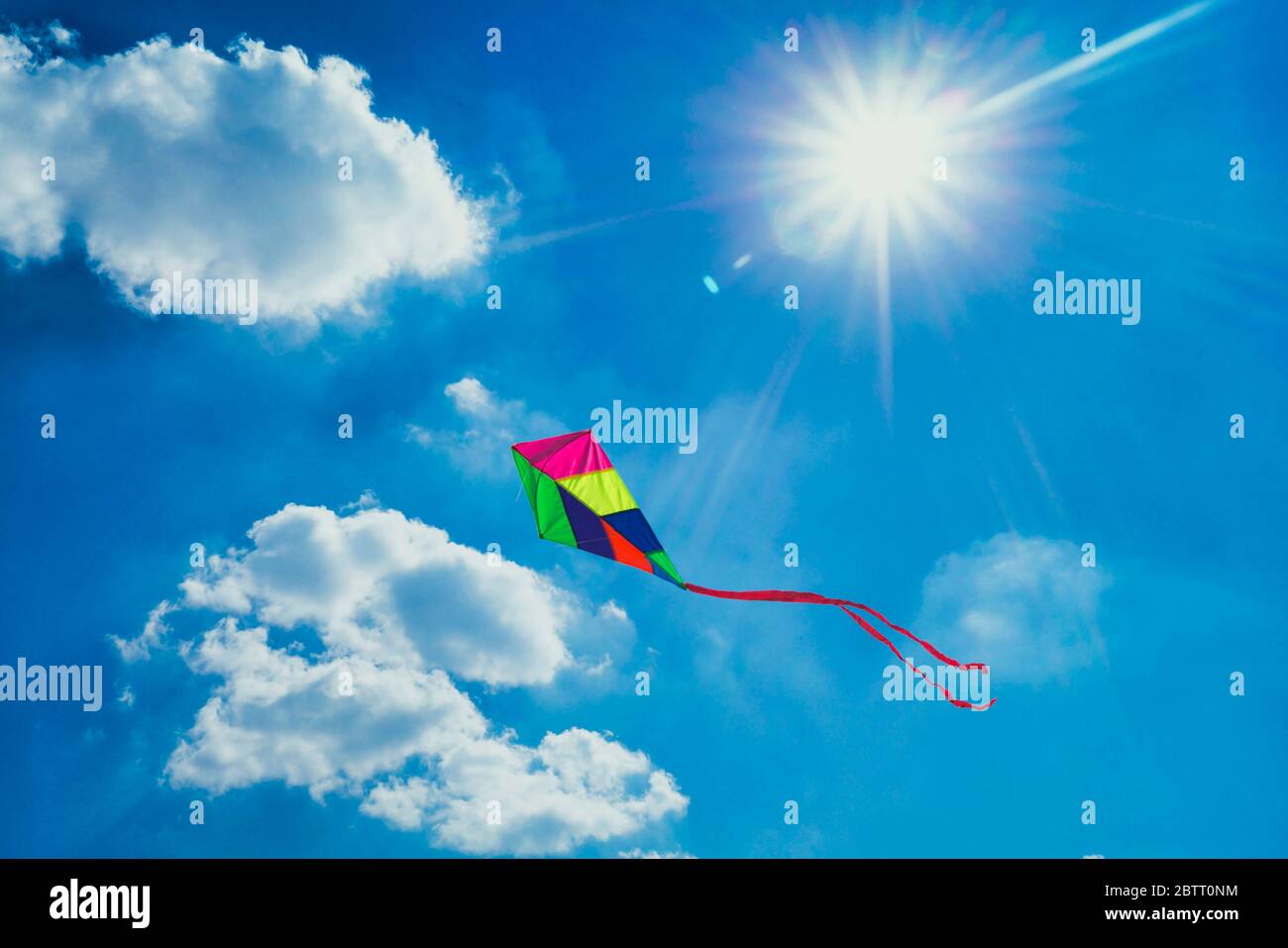 Bunte Spielzeugdrachen gegen blauen bewölkten Himmel an einem sonnigen Tag Stockfoto