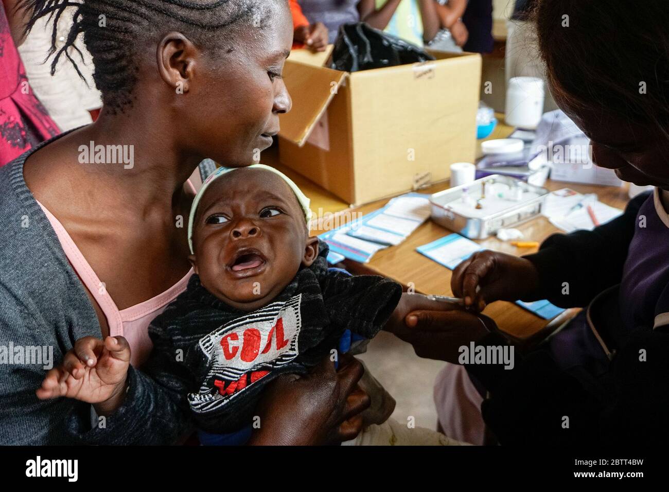 Rosalia Phiri hält ihr neun Monate altes Baby Joshua fest, als er in einer Klinik der Shine Charity in Lusaka, Sambia, einen Masern-Impfstoff erhält. Alle sechs Monate gehen die Gesundheitshelfer der Regierung in die Gemeinden, immunisieren förderungswürdige Kinder und bieten andere Gesundheitsdienste an. (Prudence Phiri, GPJ Sambia) Stockfoto