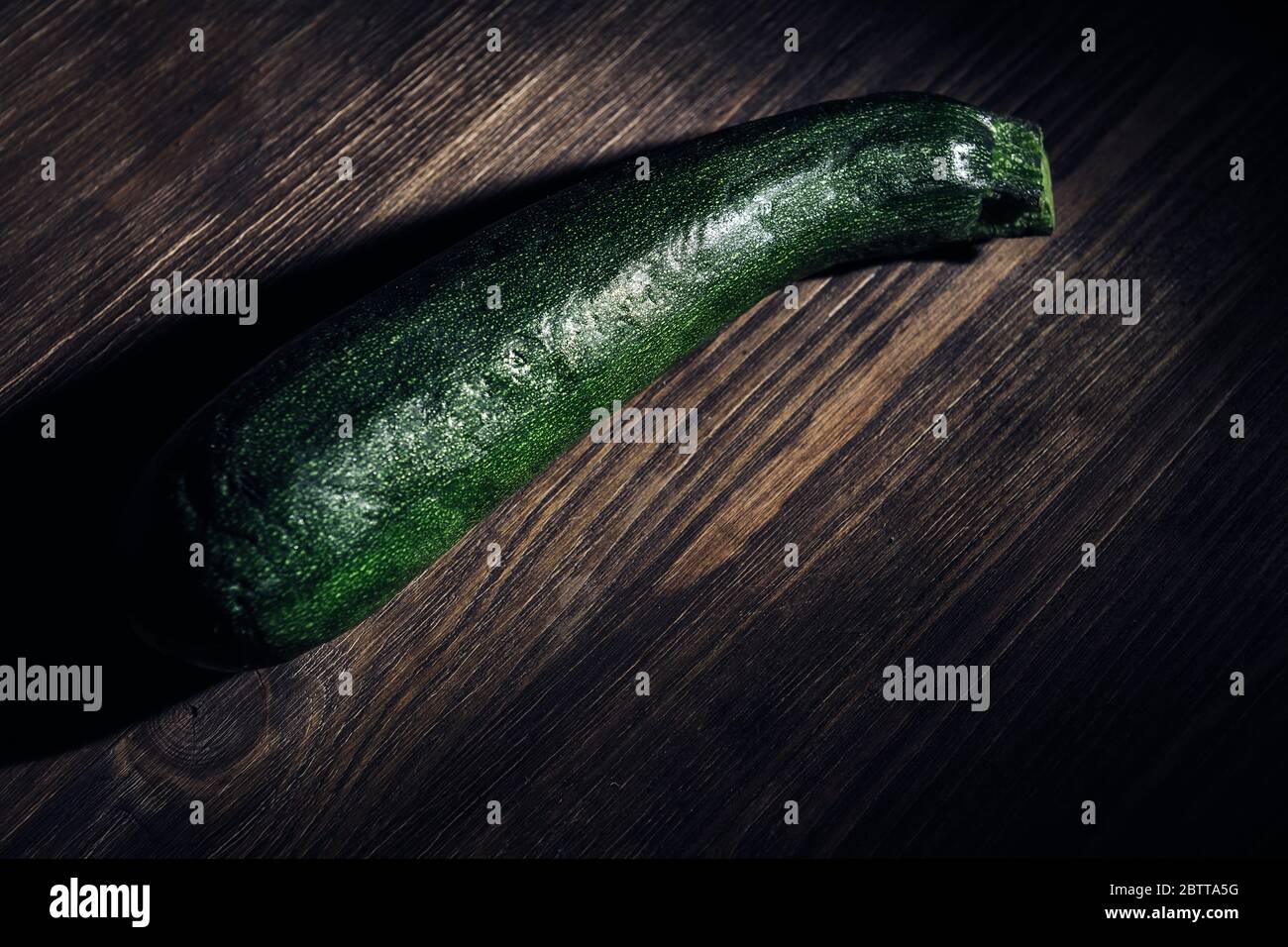 Zucchini auf einem dunklen Holz rustikalen Tisch, gesundes Essen Konzept, dunkle Lebensmittel Bild Stockfoto
