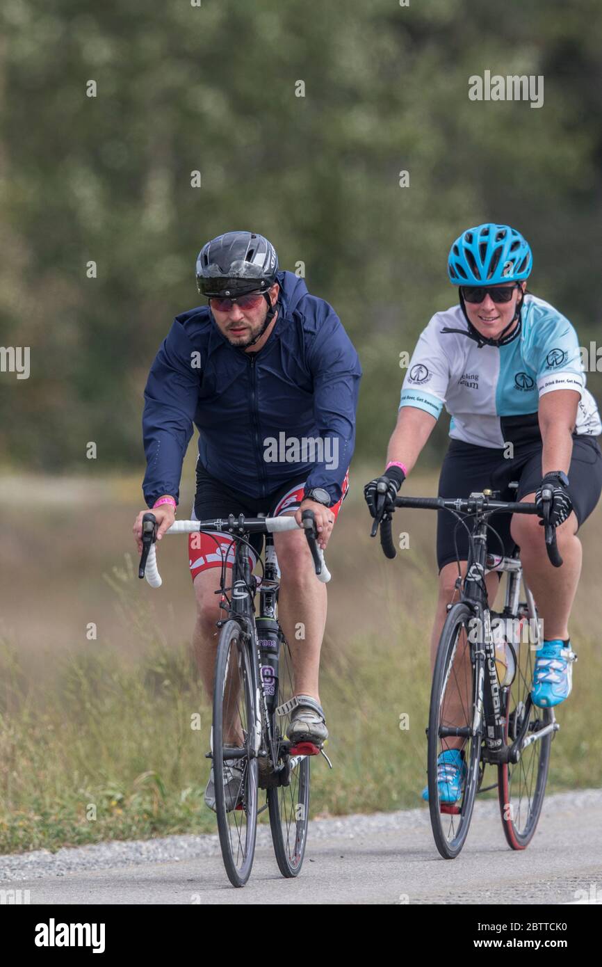 Scenic Bike Race, 2 Fahrer, in voller Rennausrüstung und Uniform. Rennen geht durch Ackerland und die Berge. Stockfoto