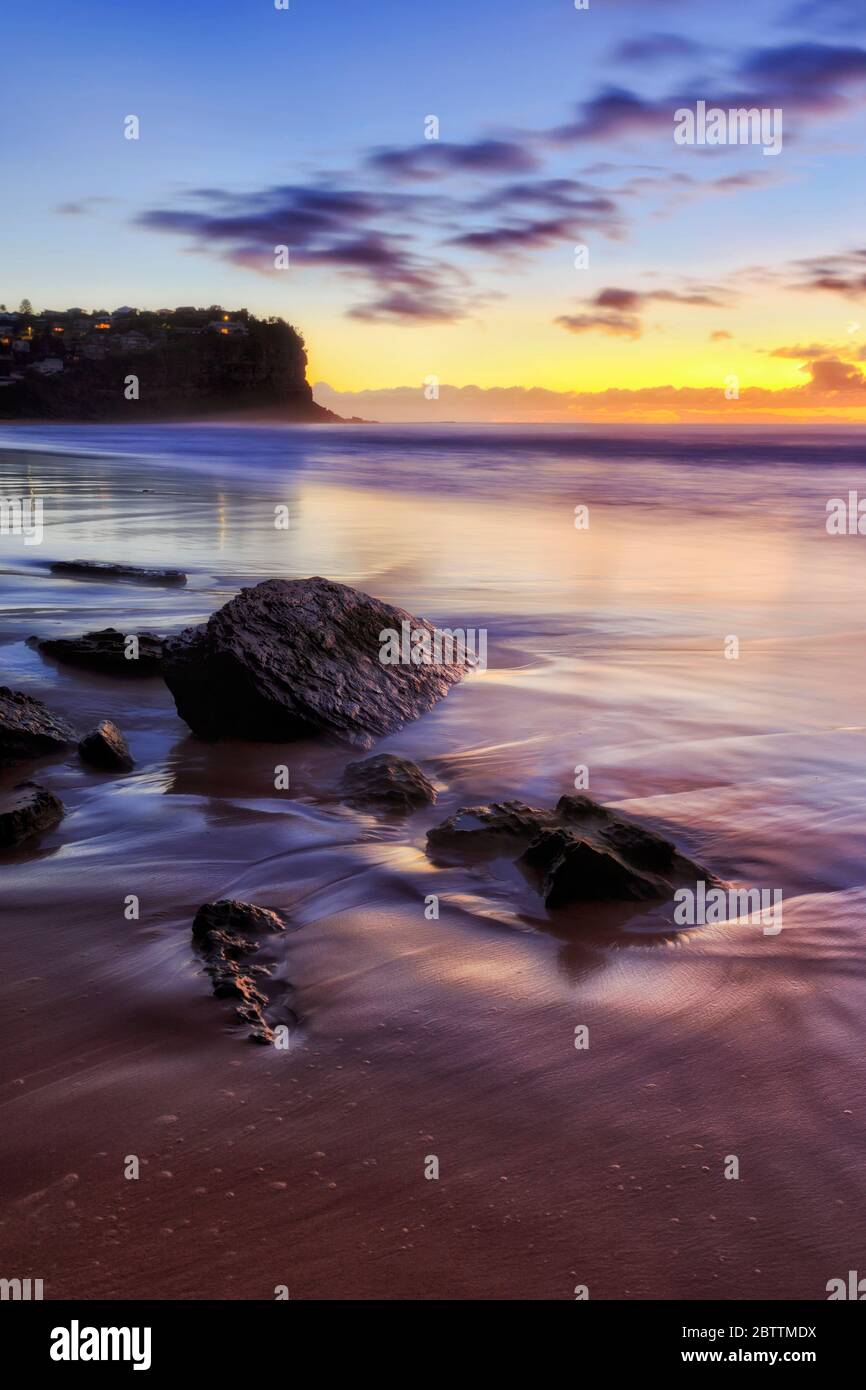 Bungan Strand bei Sonnenaufgang mit nassen Sandsteinfelsen nach Osten und aufgehender Sonne an der Pazifikküste in Sydney. Stockfoto