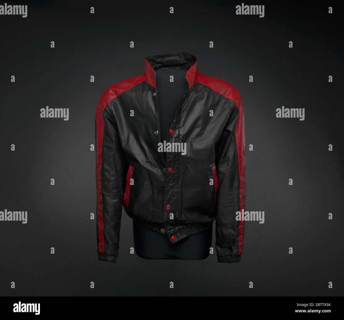 Schwarz-rote Lederjacke von Kurtis Blow. Diese schwarz-rote Lederjacke trug Kurtis Blow auf dem Cover seines Albums 'Deuce' (1981). Die Jacke im Motorradstil hat lange Ärmel, einen Stehkragen und schließt an der Vorderseite in der Mitte mit einem schwarzen Reißverschluss und fünf (5) roten Metallknöpfen. Stockfoto