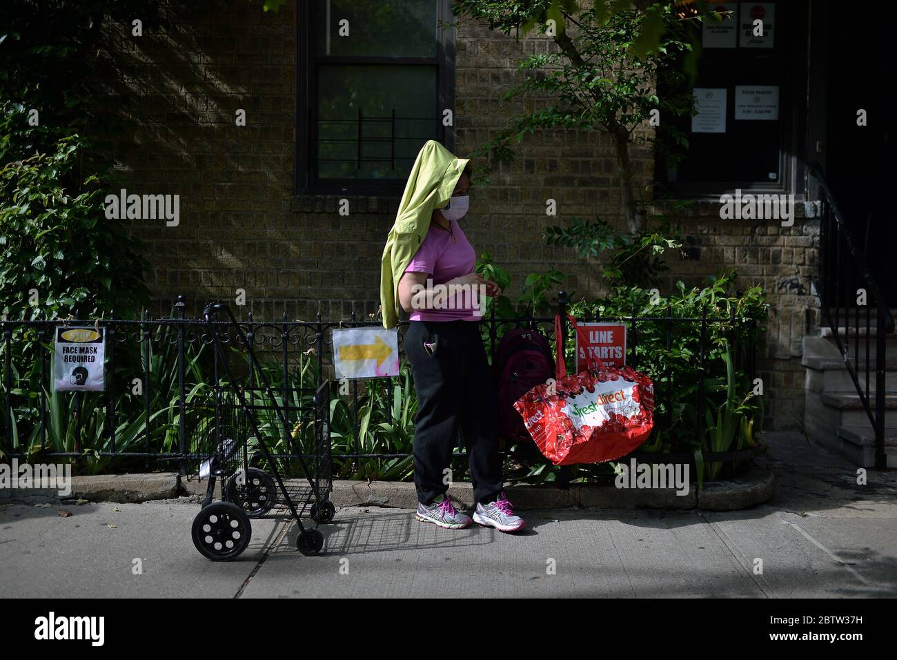 New York City, USA. Mai 2020. Menschen, die zur Zeit der COVID-19 Gesichtsmasken trugen, stehen wegen Verunsicherung der Lebensmittel in der Schlange, um gespendete Lebensmittel vom Mosaic Community Center Food Pantry, im Sunnyside-Abschnitt des Queens-Bezirks von New York City, NY, am 27. Mai 2020, zu erhalten. (Anthony Behar/Sipa USA) Credit: SIPA USA/Alamy Live News Stockfoto