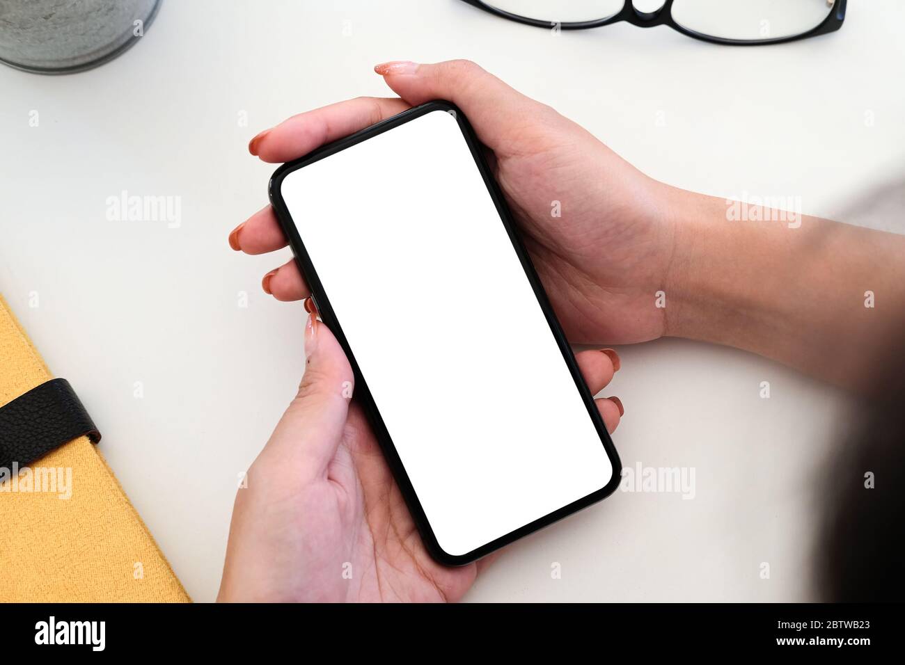 Draufsicht Frau sitzt und hält leere Bildschirm Mock-up-Handy Stockfoto
