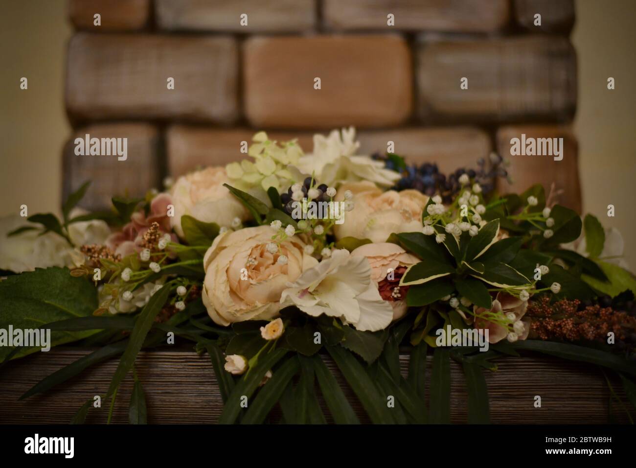 Dekorativer horizontaler Blumenstrauß auf der Tafel unten auf Backstein-Hintergrund. Stockfoto