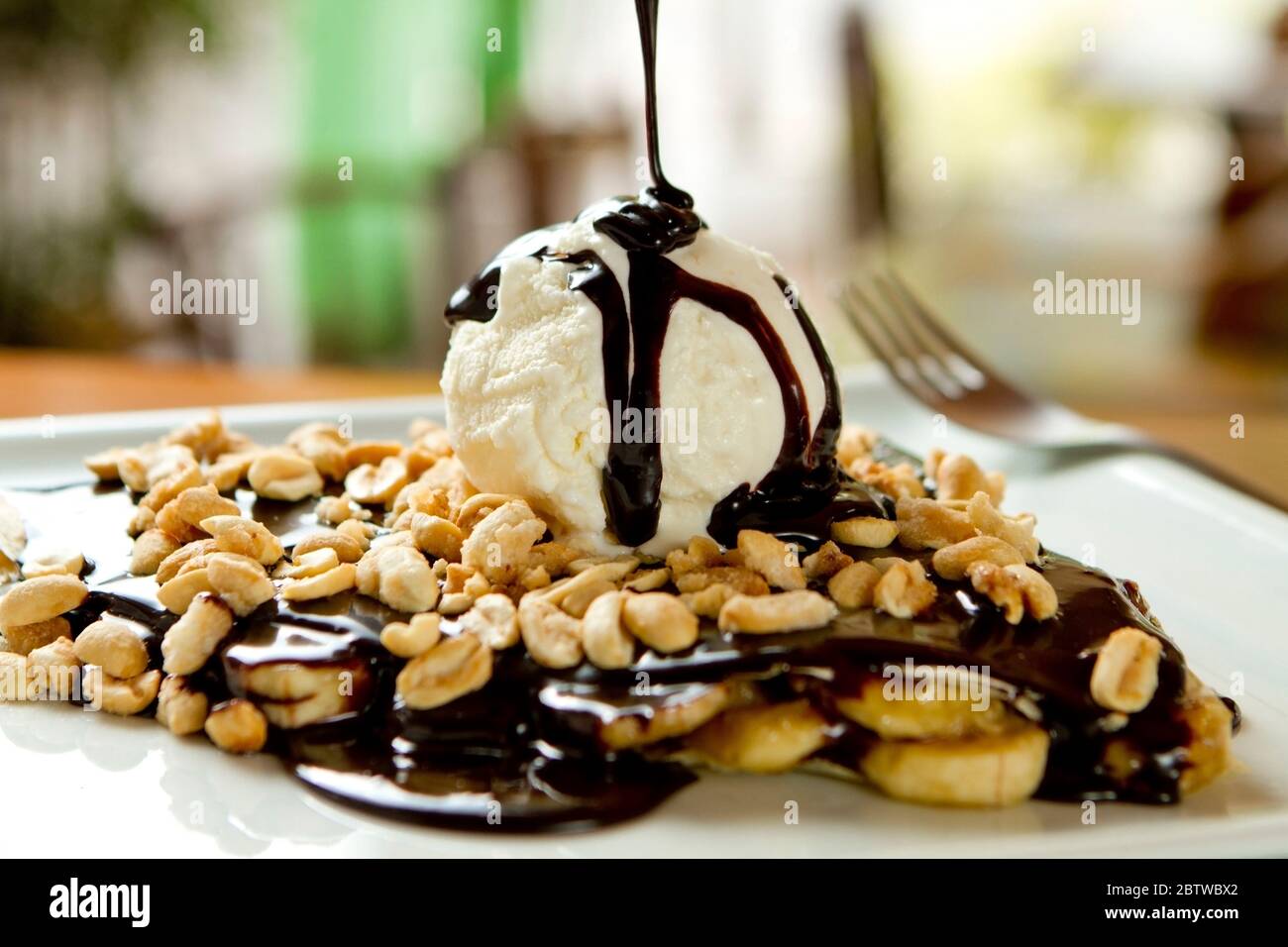 Schokolade Crepe und Vanille Eis, Bananenscheiben und Erdnüsse Toppings. Sirup tropft von oben. Leckeres, süßes Gourmet-Dessert, französische Küche Stockfoto Schokolade Crepe und Vanille Eis, Bananenscheiben und Erdnüsse Toppings. Sirup tropft von oben. Leckeres, süßes Gourmet-Dessert, französische Küche Stockfoto