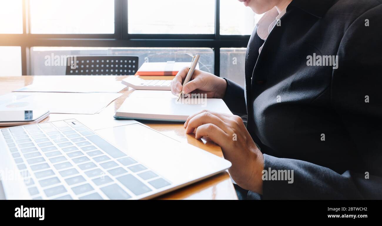 Eine Frau Hand hält einen Stift notieren einige Daten auf Notizblock für finanzielle Berechnung Stockfoto