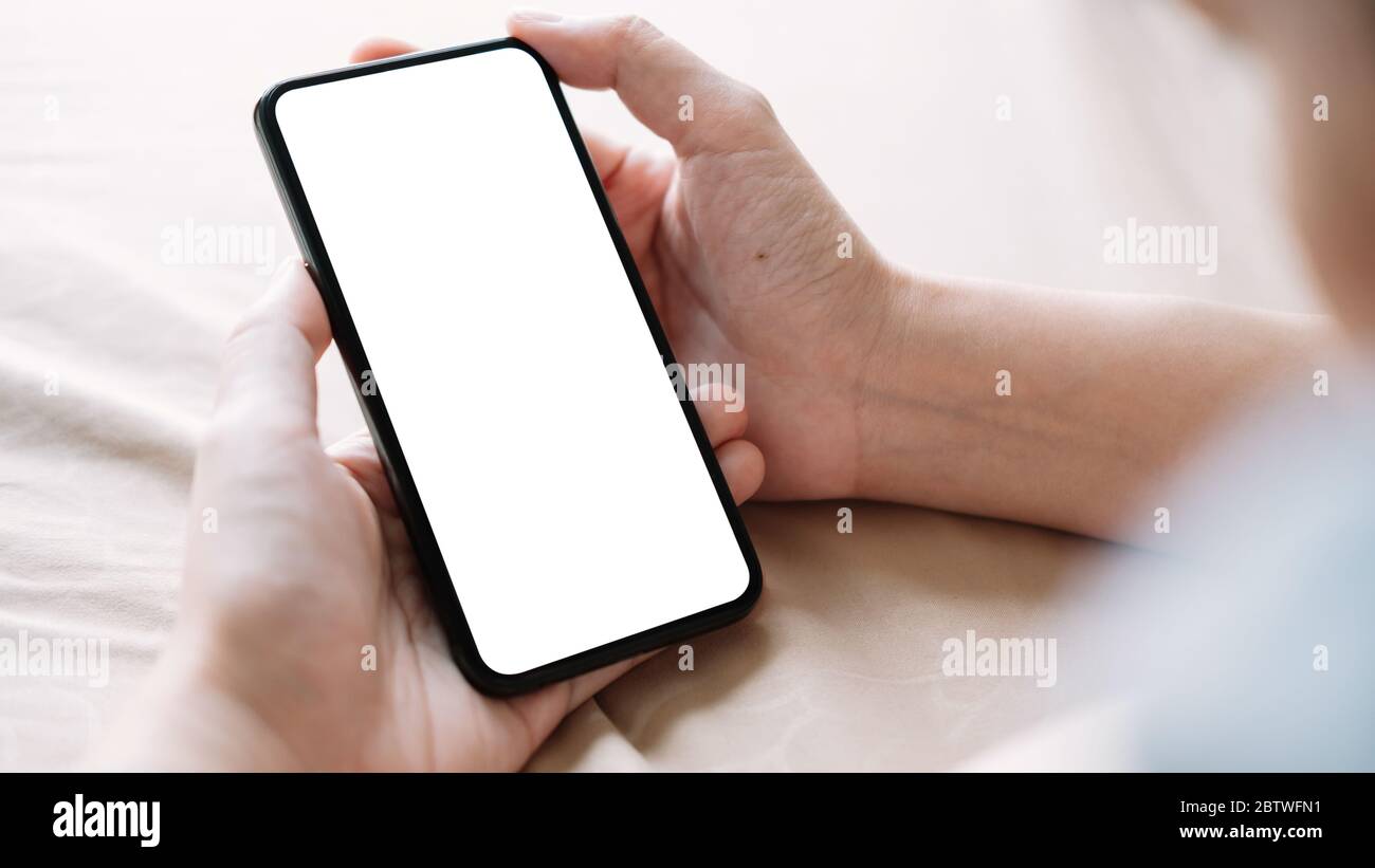 Nahaufnahme der Hand einer Frau mit einem Smartphone mit weißem Bildschirm zu Hause Stockfoto