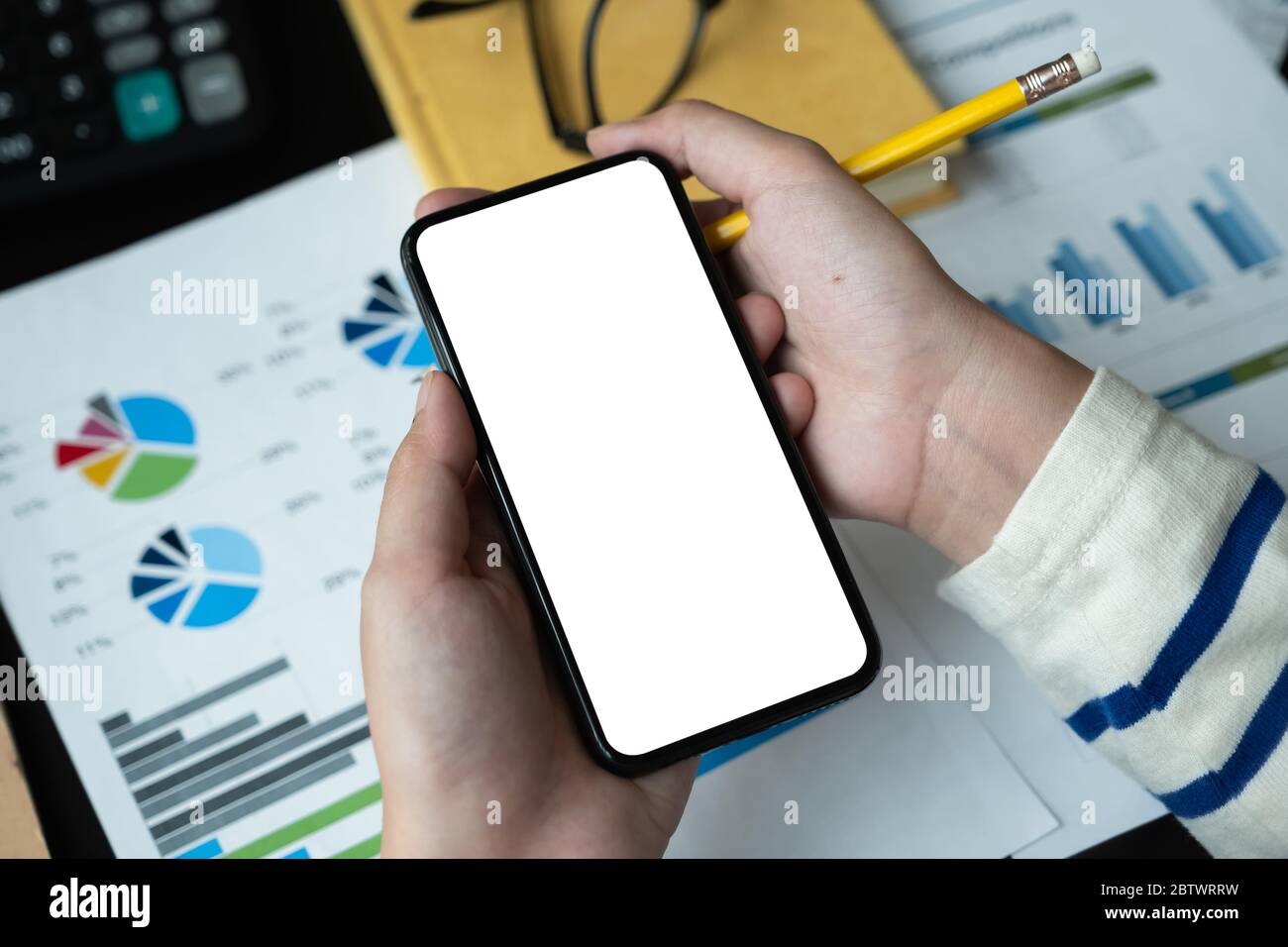 Draufsicht der Frau mit leerem Bildschirm Smartphone im dunklen trendigen Arbeitsplatz für die Buchhaltung Finanz Stockfoto