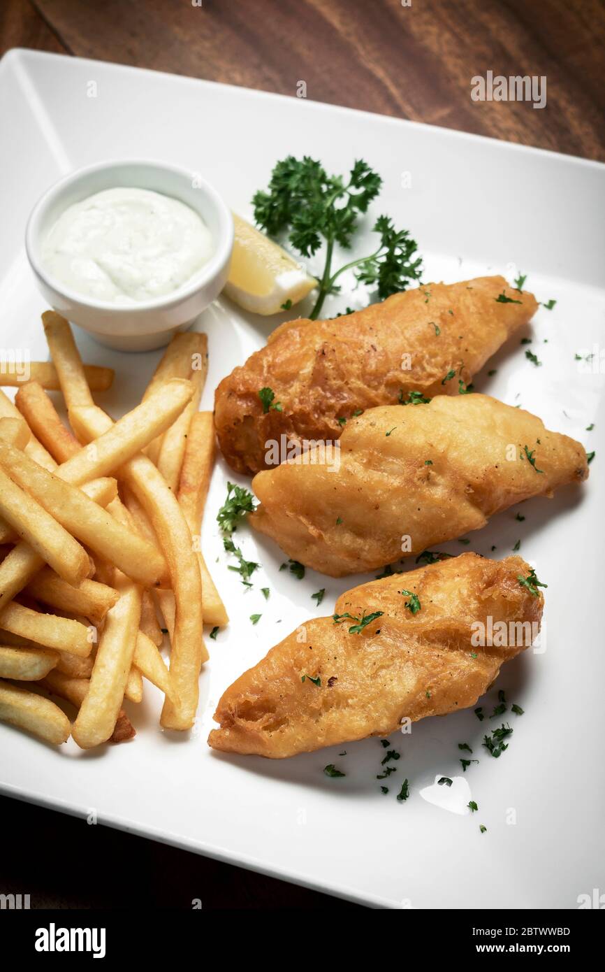 traditionelles britisches Fish & Chips-Gericht auf einem klassischen Holztisch Stockfoto