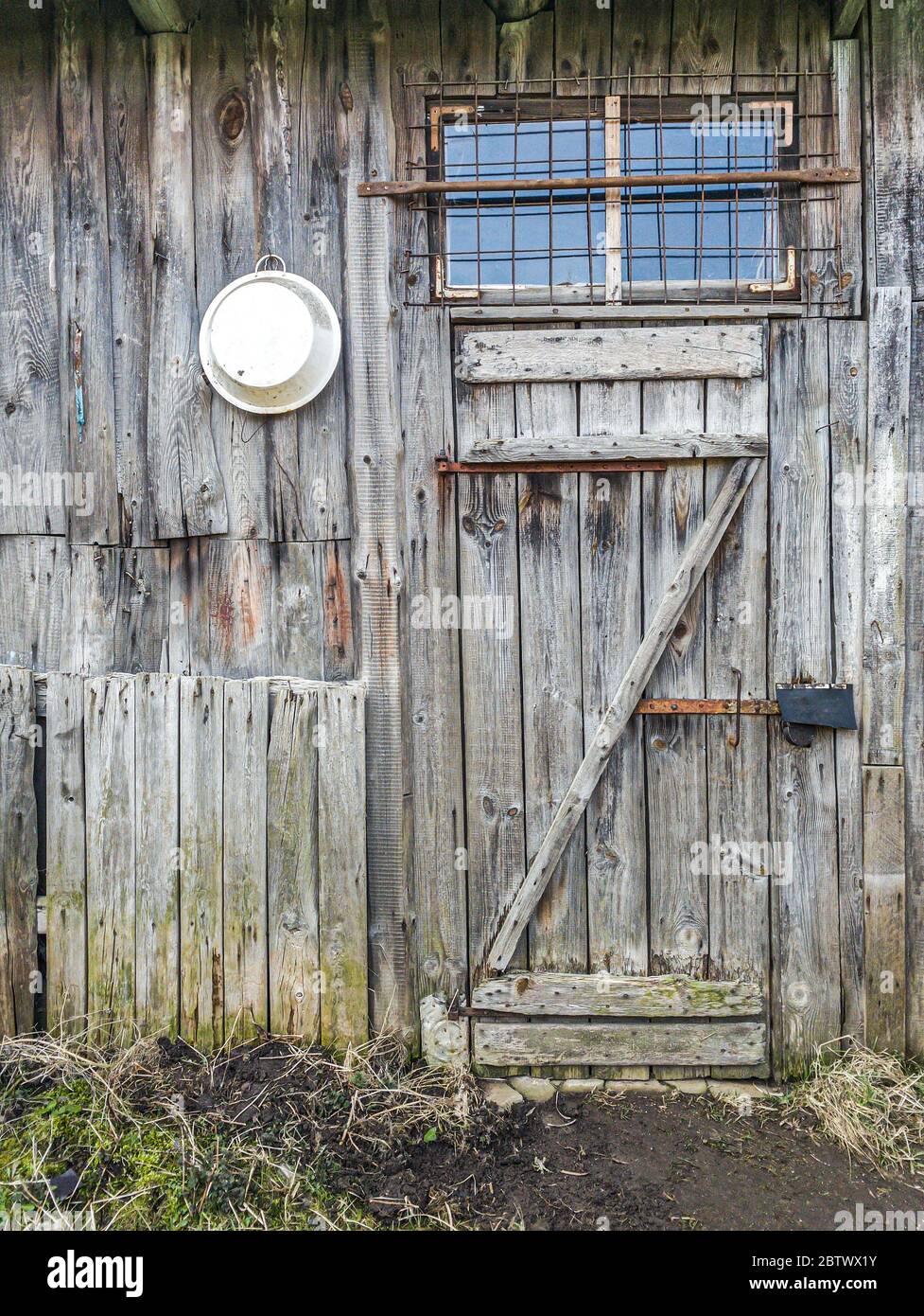 Alte verwitterte Holzschuppenwand mit geschlossener Tür und Fenster Stockfoto