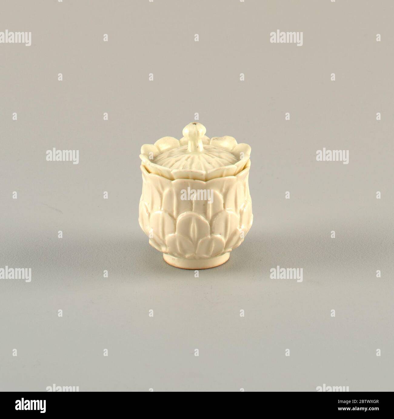 Covered Custard Cup. Forschung in ProgressAuf dem einfachen Fuß, eine umgekehrte glockenförmige Tasse; die Außenseite mit Relief-Schnitt Artischockenblätter bedeckt, bilden scalloped Rand über inneren Rand. Cover mit leichten Kuppel, mit Relief-niedlichen Artischocken Blätter bedeckt, und eine Reihe von stehenden Blättern um den Rand. Stockfoto