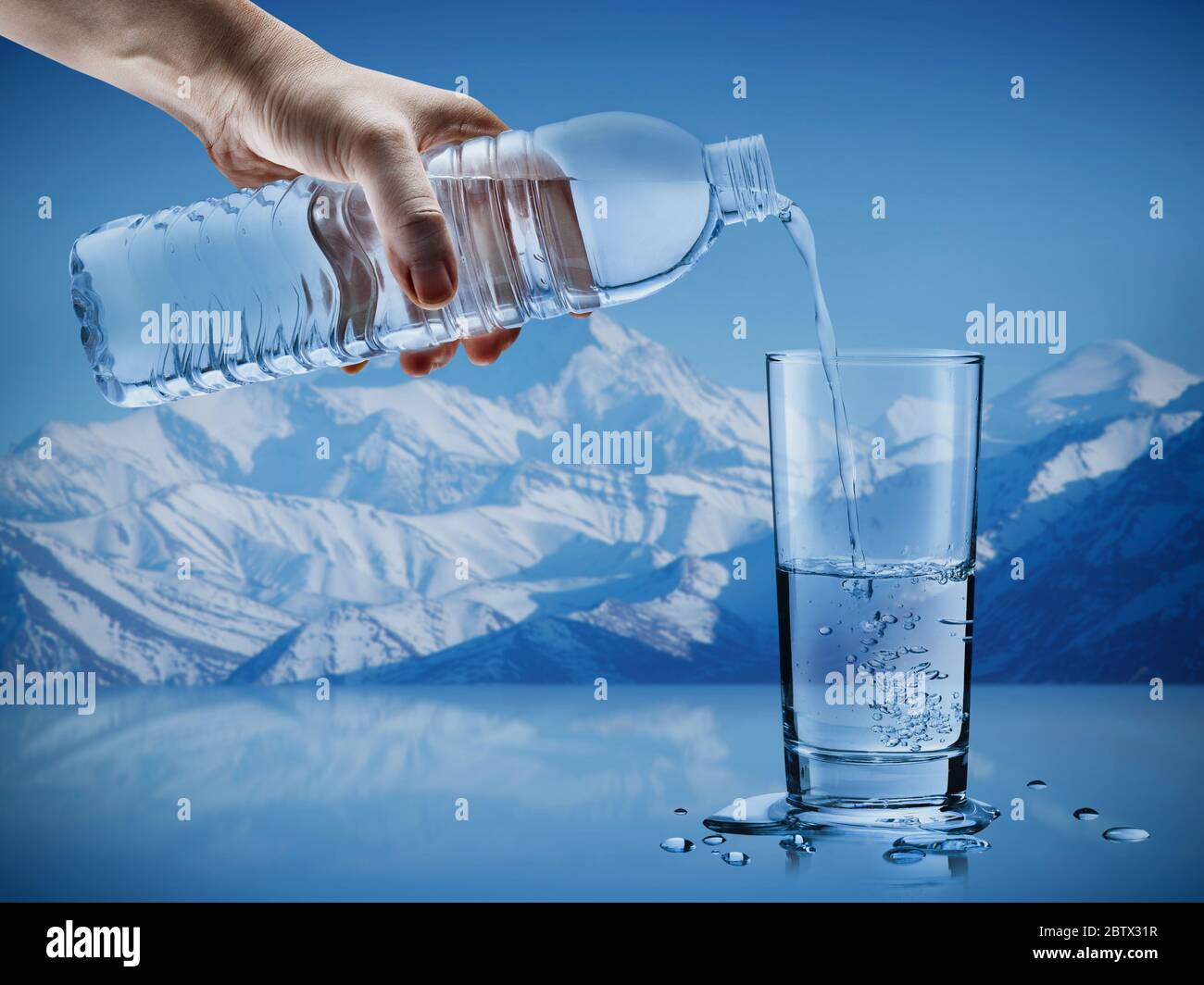 Hand gießen Mineralwasser aus der Flasche in ein Glas mit Wassertropfen im Eisberg Hintergrund, Gesundheit und Schönheit Hydratation Konzept Stockfoto