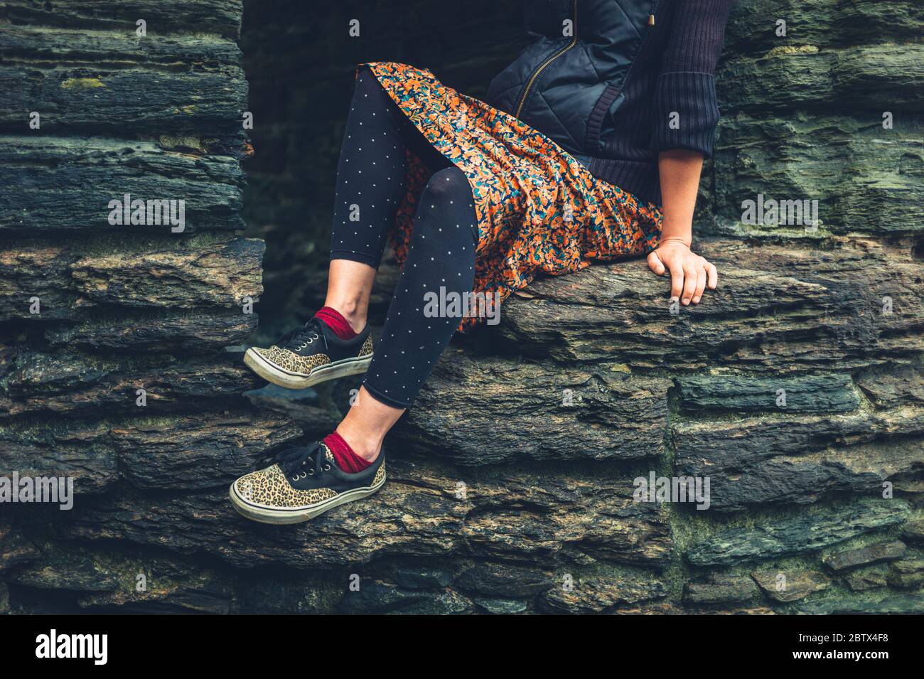 Eine schwangere junge Frau sitzt auf einer Mauer in einer alten Festung Stockfoto