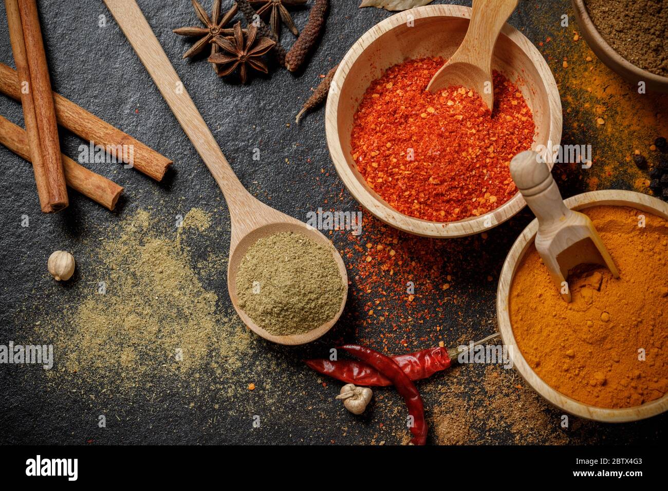 Kräuter und Gewürze über schwarzem Stein. Ansicht von oben Stockfoto